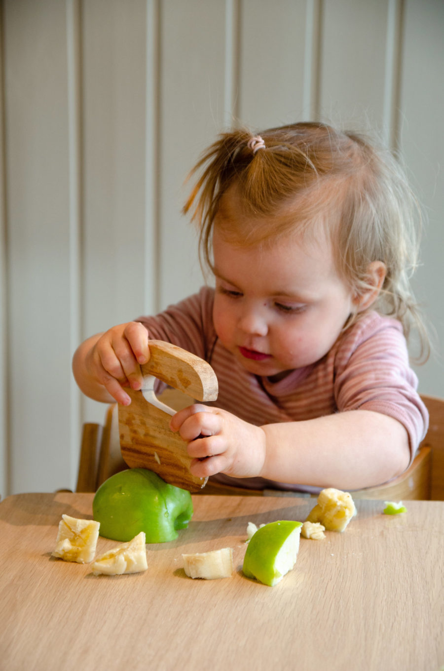 Liten jente skjærer eple med barnekniven