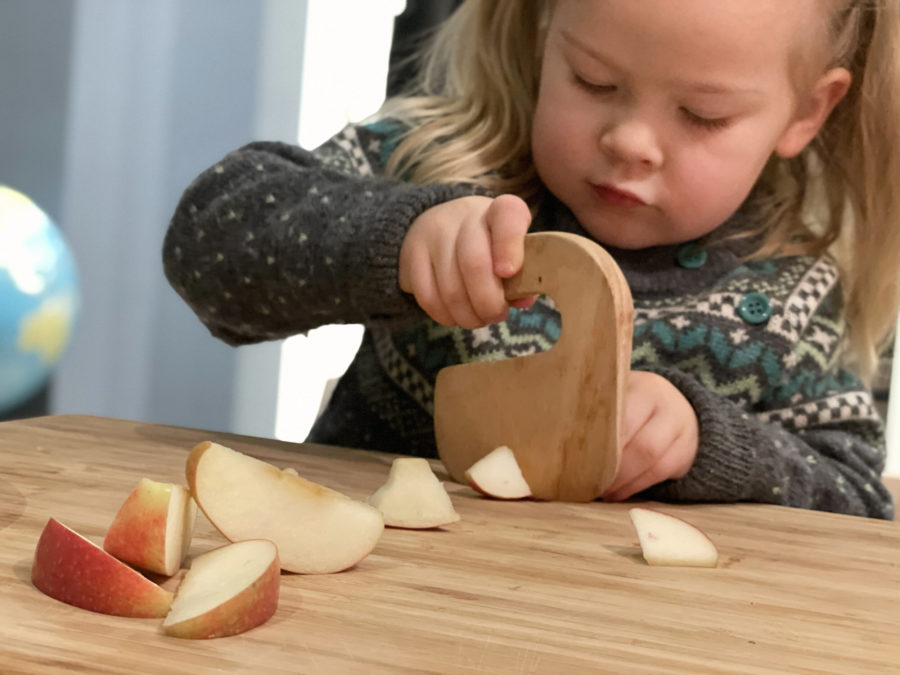 Liten jente skjærer eple med barnekniven